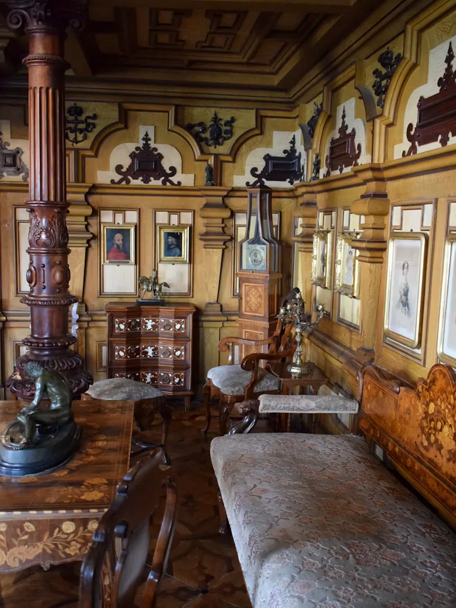 Witryna z porcelaną w świetle okna, obok krzesło gięte